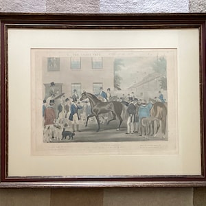 May include: A framed print of a vintage illustration depicting a group of people gathered around a horse in a courtyard. The print is titled "The Great Fair" and features a horse with a rider, other horses, and several people in 19th-century attire.