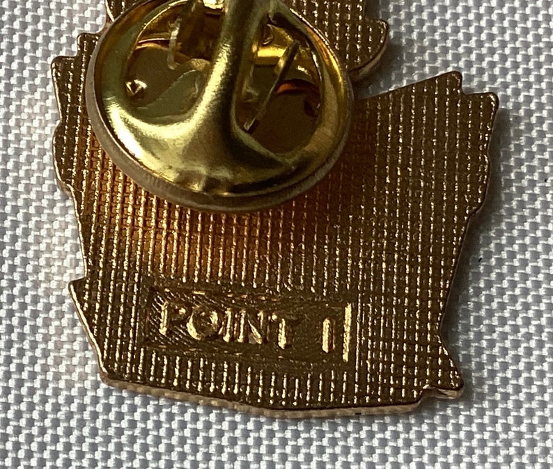 Op de afbeelding: Gouden metalen pin met een gedetailleerd ontwerp. De achterkant van de pin heeft de tekst "POINT II" gegraveerd.