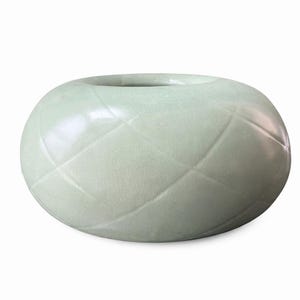 May include: A pale green, round ceramic vase with a textured, diamond-patterned surface. The vase has a wide opening at the top and a smooth, glossy finish. The overall shape is spherical, and the design is simple and elegant.