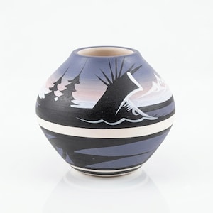 May include: A rounded ceramic vase featuring a matte finish with a painted landscape scene. The design includes black silhouettes of pine trees and a mountain peak against a gradient of soft blue and white, accented by horizontal white bands.