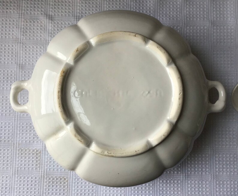 May include: White ceramic serving dish with a scalloped edge and two handles. The bottom of the dish has the text "Germany" printed on it.