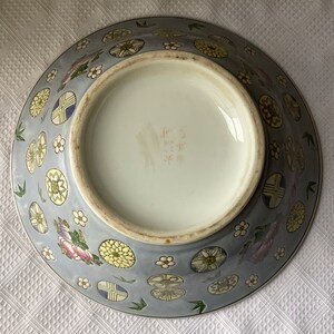 May include: A large, blue and white porcelain bowl with a floral and geometric design. The bowl has a round shape and a flat bottom. The bottom of the bowl has a mark in Japanese characters.