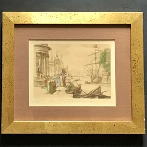 May include: A framed print of a watercolor painting depicting a bustling harbor scene with boats, buildings, and people. The print is in a gold frame with a light brown mat.