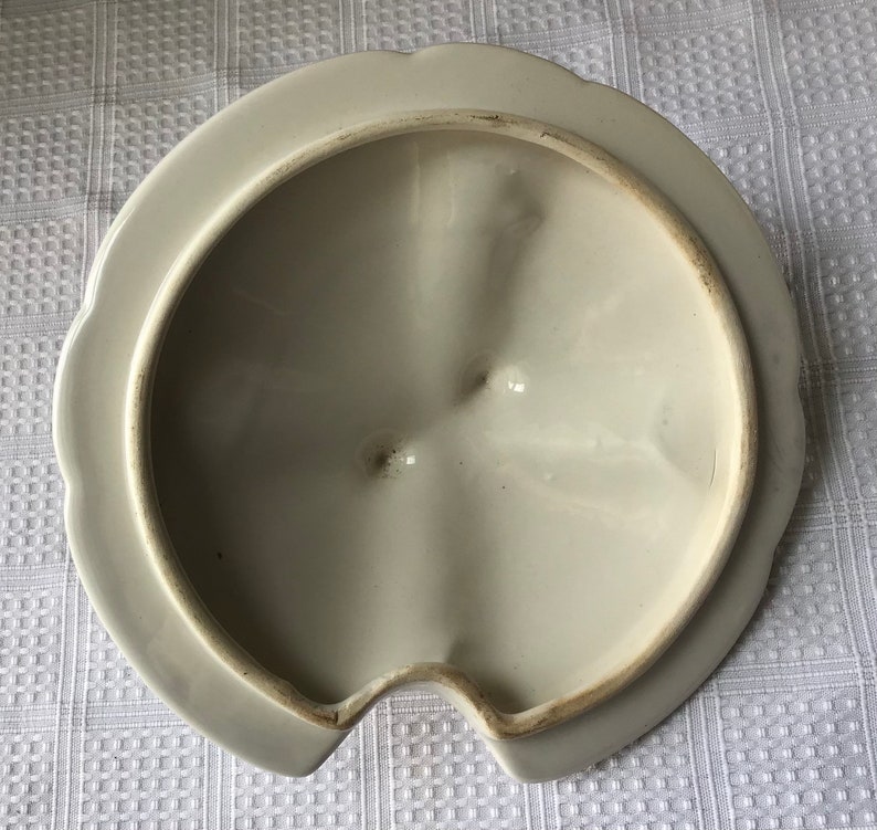 May include: White ceramic lid with a scalloped edge and a small spout. The inside of the lid has a smooth, white finish.