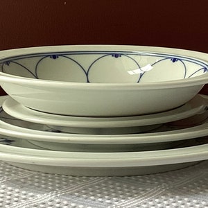 May include: A set of white ceramic plates and a bowl with a blue and white floral design.