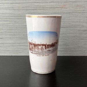 May include: A white ceramic mug with a black handle and the text "But First, Coffee" in a black, handwritten-style font. The mug is on a white surface.