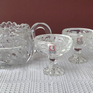 May include: A set of four clear glass serving dishes with a cut glass design. The dishes have a pedestal base and are perfect for serving desserts or appetizers.