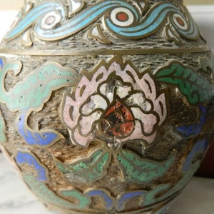 K&ouml;nnte beinhalten: Eine vintage Cloisonn&eacute;-Vase mit floralem Design. Die Vase ist mit blauem, gr&uuml;nem, wei&szlig;em und rotem Email verziert. Die Vase ist aus Metall und hat eine strukturierte Oberfl&auml;che.
