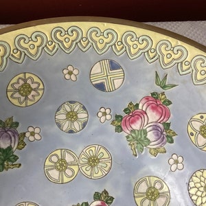 May include: A large, round, blue and white ceramic bowl with a yellow rim and intricate floral and geometric designs. The bowl features a variety of flowers, leaves, and stylized patterns.