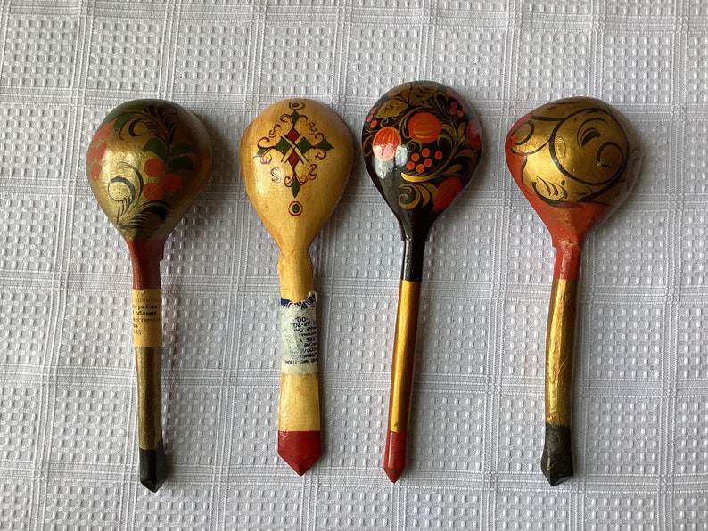 May include: Four wooden spoons with hand-painted designs. The spoons are decorated with floral patterns, geometric shapes, and gold accents. The spoons are all different colours, including red, black, and gold.