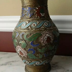 K&ouml;nnte beinhalten: Eine Messingvase mit Cloisonn&eacute;-Design. Die Vase ist mit floralen und Wellenmustern in Blaut&ouml;nen, Gr&uuml;n, Rosa und Rot verziert.