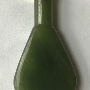May include: A dark green jade pendant in the shape of a bottle with a gold top and a loop for hanging.