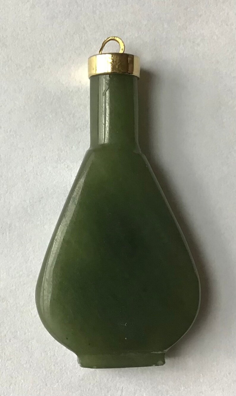 May include: A dark green jade pendant in the shape of a bottle with a gold top and a loop for hanging.