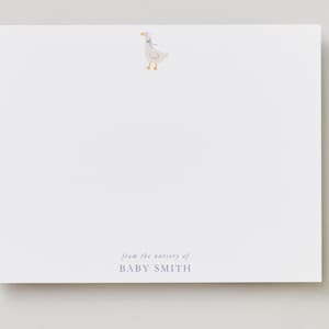 May include: White stationery card with a watercolor illustration of a goose wearing a blue bow. The text "from the nursery of BABY SMITH" is printed in a dark blue font at the bottom of the card. The card is rectangular.