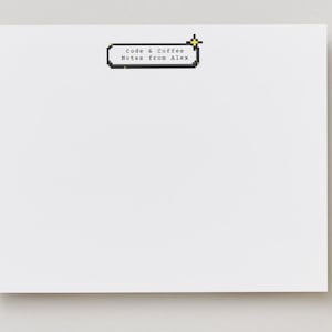 May include: A white notepad with a pixelated speech bubble graphic that reads "Code & Coffee Notes from Alex." The notepad is blank, with a simple design, and is likely used for taking notes or jotting down ideas.