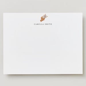 Op de afbeelding: Wit briefpapier met een bruine en witte ijshoornillustratie en de tekst "Camilla Smith" in zwart gedrukt.