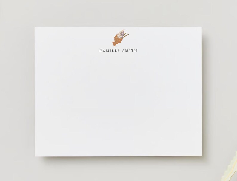 Op de afbeelding: Wit briefpapier met een bruine en witte ijshoornillustratie en de tekst "Camilla Smith" in zwart gedrukt.