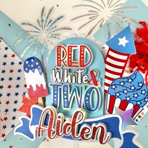 May include: Red, white, and blue cake topper with the words "Red White & Two Aiden" and a firework, cupcake, and popsicle design.