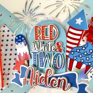 May include: Red, white, and blue cake topper with the words "Red White & Two Aiden" and a firework, cupcake, and popsicle design.