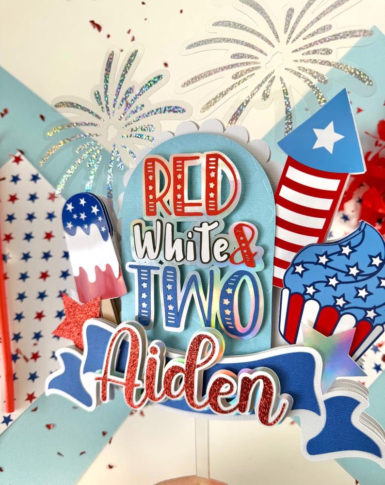 May include: Red, white, and blue cake topper with the words "Red White & Two Aiden" and a firework, cupcake, and popsicle design.