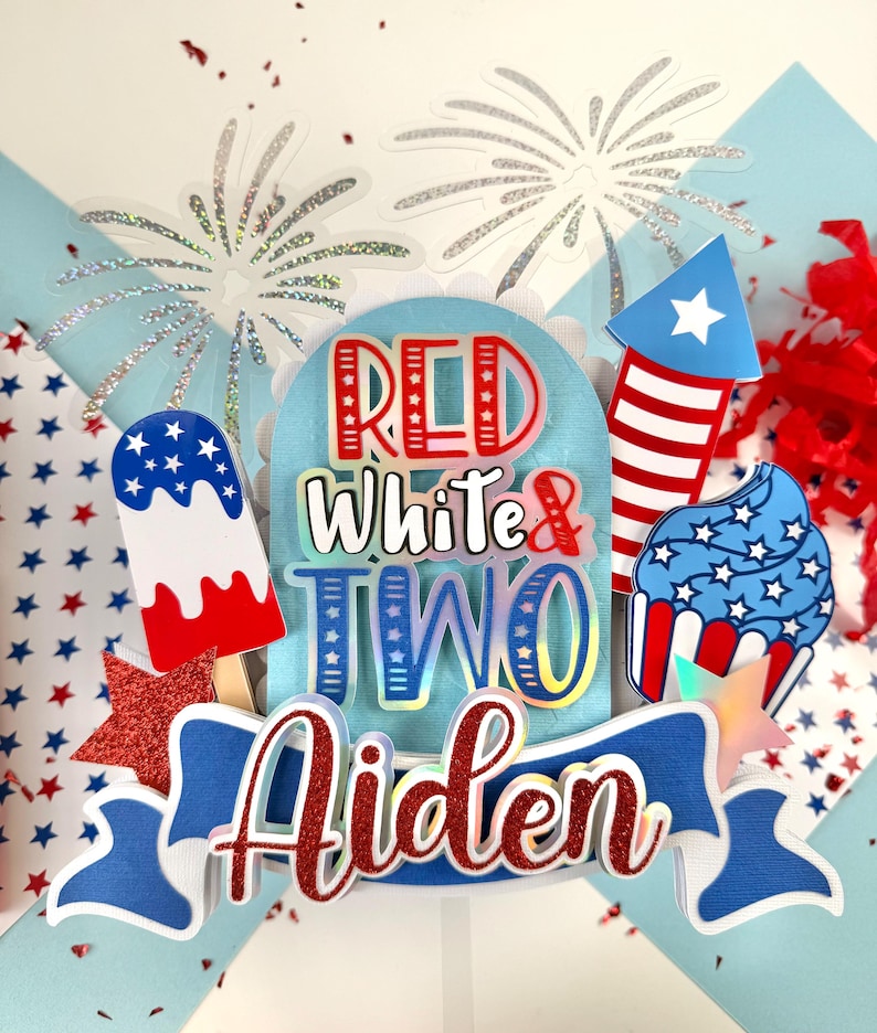 May include: Red, white, and blue cake topper with the words "Red White & Two" and the name "Aiden". The topper features a firework, a cupcake, and an ice cream pop.