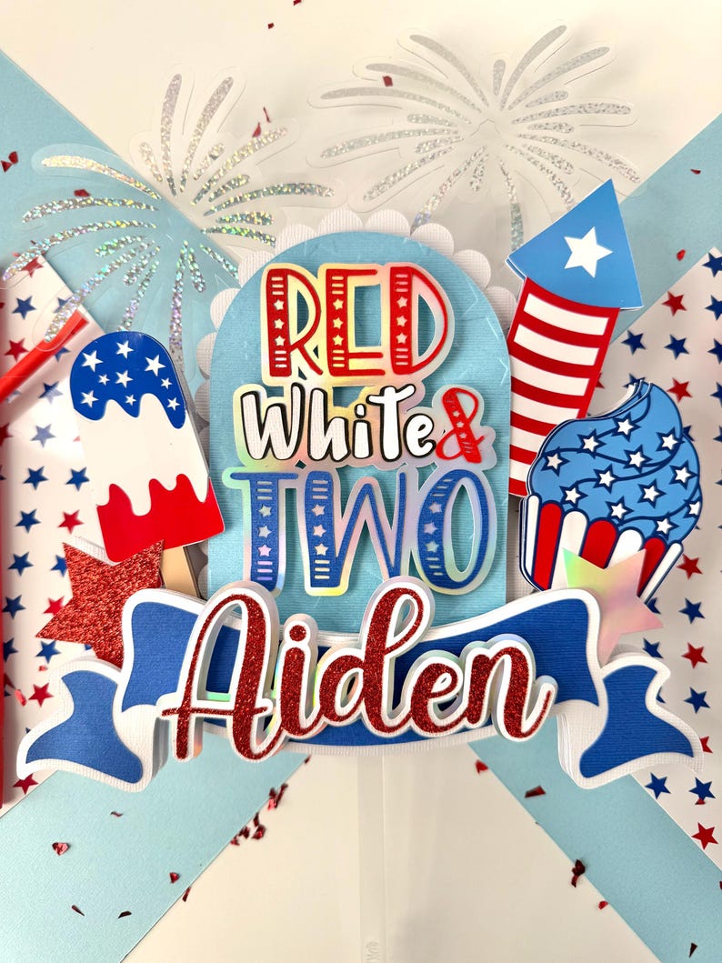May include: Red, white, and blue cake topper with the words "Red White & Two Aiden" and a firework, cupcake, and popsicle design.