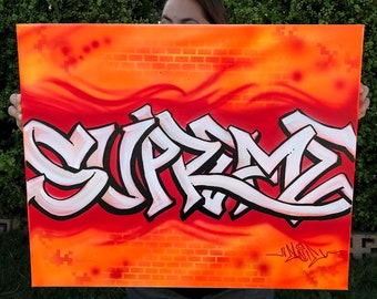 May include: An orange and red canvas art piece with the word "SUPREME" in large white graffiti-style lettering. The background features a brick pattern and wavy lines, with a signature in the bottom right corner.