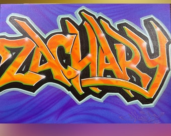 May include: A canvas featuring the name "ZACHARY" in vibrant graffiti style. The letters are orange with black outlines and a light blue shadow, set against a swirling purple background. The artwork has a bold, urban aesthetic.