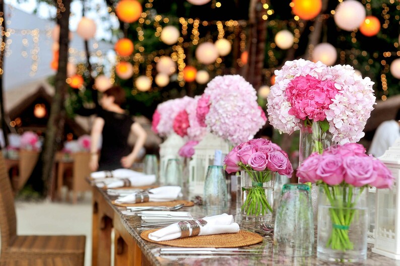 Peut inclure: Une table dress&eacute;e avec des fleurs roses et blanches dans des vases en verre. La table est dress&eacute;e avec des serviettes blanches, des couverts et des sets de table. Les fleurs sont dispos&eacute;es en diff&eacute;rentes tailles et formes, cr&eacute;ant une pi&egrave;ce ma&icirc;tresse magnifique et &eacute;l&eacute;gante.