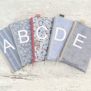 May include: Five zippered pouches with different patterns and colors. Each pouch has a letter printed on it, spelling out the word "ABCDE".