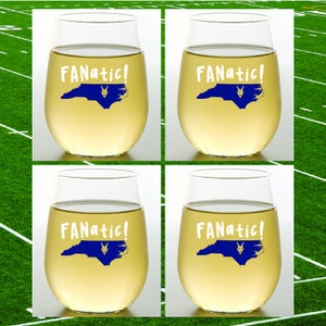 May include: Four stemless wine glasses filled with a light-colored liquid. Each glass has the word "FANATIC!" in white, along with a blue outline of North Carolina and a graphic. The background is a green field with white lines.