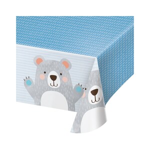 May include: Blue plastic tablecloth with a gray and white bear design. The tablecloth features a striped pattern and a blue polka dot pattern.