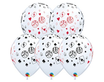 May include: Five white balloons with a casino theme. The balloons are decorated with red and black playing card suits, dice, and playing cards. The balloons are inflated and ready for a party.