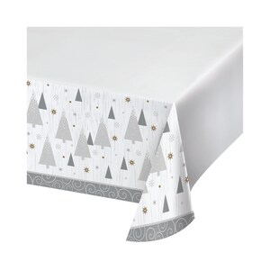 May include: White plastic tablecloth with a silver and gold pattern of stylized Christmas trees and snowflakes. The tablecloth has a scalloped edge.