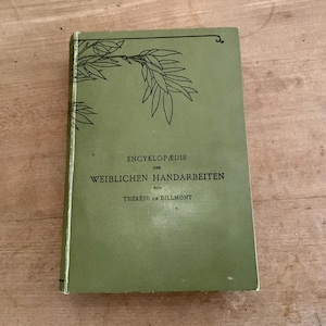 Könnte beinhalten: Ein Vintage-Buch mit grünem Einband, betitelt "ENCYKLOPÄDIE DER WEIBLICHEN HANDARBEITEN" und dem Namen des Autors, Th. de Dillmont. Das Cover hat ein schwarzes Blattdesign in der oberen linken Ecke.
