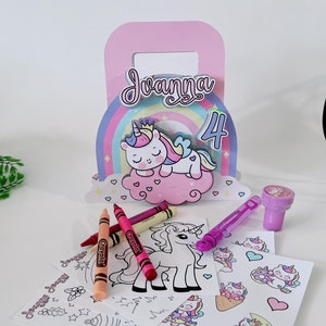 Può includere: Una scatola regalo per feste a tema unicorno con un manico rosa, un design arcobaleno e il nome "Jvanna" stampato sul davanti. La scatola include una pagina da colorare di unicorno, matite colorate, adesivi e una bacchetta per le bolle.