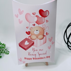 May include: A Valentine's Day card featuring a cute teddy bear holding heart-shaped balloons. The card is pink with a red gift box and the text "You are Beary Special Happy Valentine's Day."