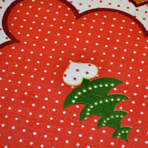 May include: Red and white polka dot fabric placemat with a green and white Christmas tree design.