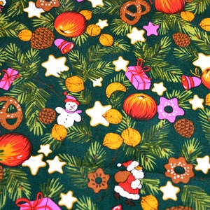 May include: A green fabric with a repeating pattern of Christmas-themed illustrations. The pattern includes pine branches, stars, presents, apples, pretzels, gingerbread cookies, and snowmen.