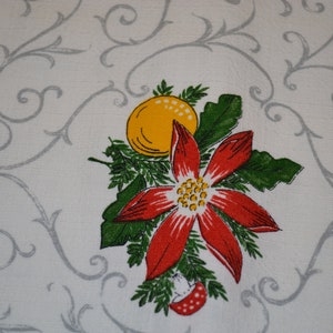 May include: A white fabric with a gray floral pattern and a red poinsettia with a yellow center and a yellow orange ornament.
