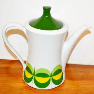 May include: White ceramic coffee pot with a green lid and a geometric design in green and yellow.