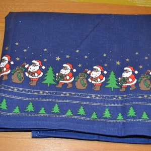 May include: A blue tablecloth with a repeating pattern of Santa Claus figures carrying bags of gifts and Christmas trees. The pattern is outlined in gold and includes small gold stars.