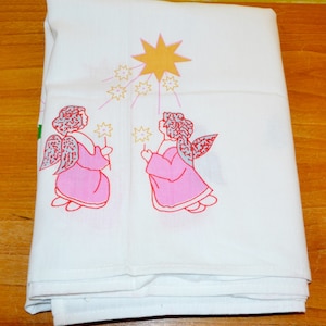 May include: White cotton tea towel with a pink and red embroidered design of two angels holding stars. The angels are facing each other and are standing under a large yellow star.