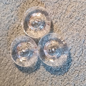 May include: Three clear plastic buttons with a raised design. The buttons have two holes each.