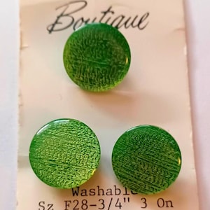 May include: Three round, textured, bright green buttons on a vintage tag. The tag reads "Boutique" and "Washable". Each button is approximately 0.75 inches in diameter.
