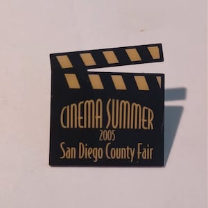 May include: Black and gold clapboard with the text "Cinema Summer 2005 San Diego County Fair"