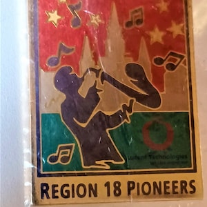 May include: A square pin featuring a silhouette of a musician playing a brass instrument, musical notes, and stars against a red and gold background. The text "REGION 18 PIONEERS" is at the bottom.