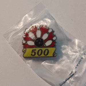 May include: A red, white, and black bowling pin pinback button with a yellow banner that says "500".