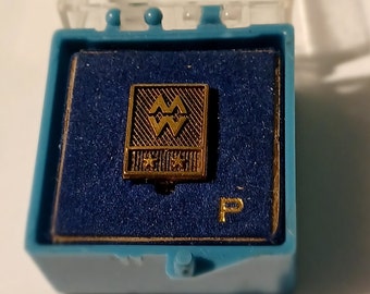 May include: A gold-colored pin with a stylized image of the astrological sign Aquarius. The pin is in a blue velvet box with a white 'P' printed on the bottom.