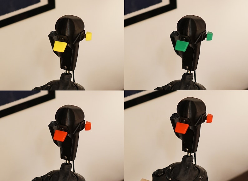 May include: A black joystick with interchangeable colored buttons: yellow, green, and orange. The joystick is mounted on a black base and has a unique, angular design. The image is a composite of four different views of the same joystick.